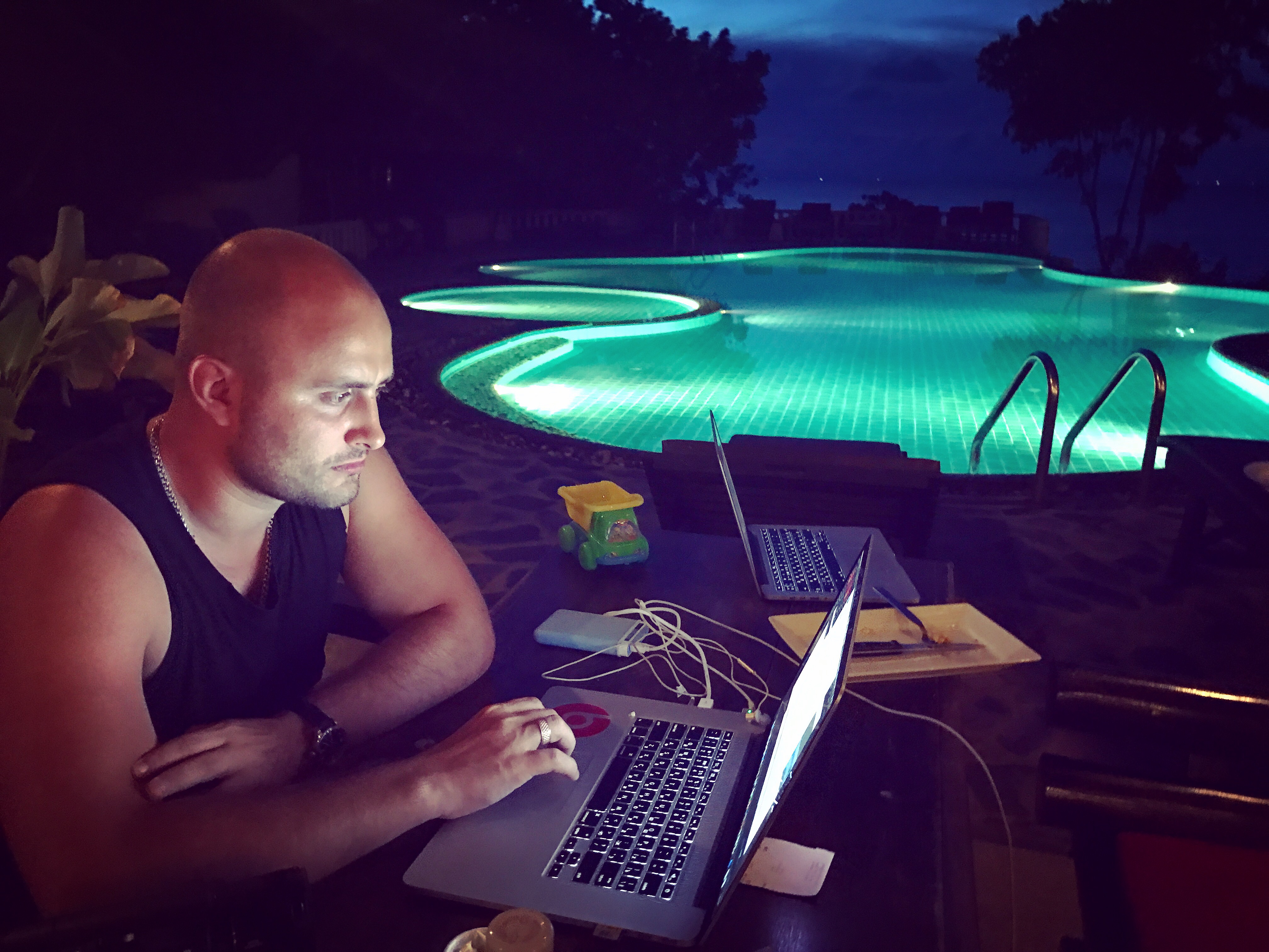 Igor Graf working on a laptop by the pool at night
