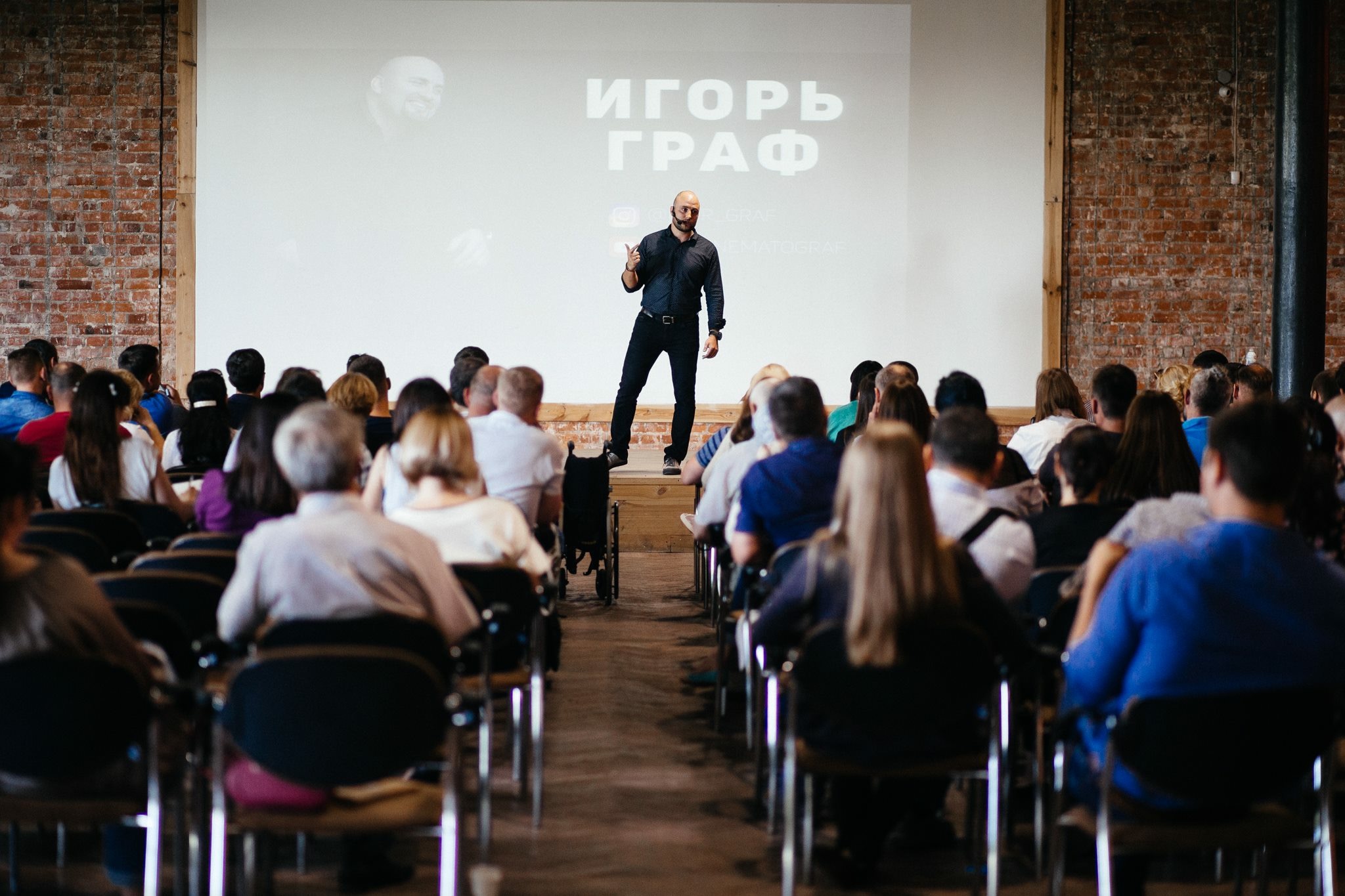 Igor Graf speaking on stage to a full audience